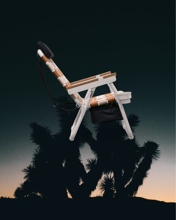 PARKIT Eclipse Recliner folding outdoor chair with padded headrest and storage, creative desert sunset background.