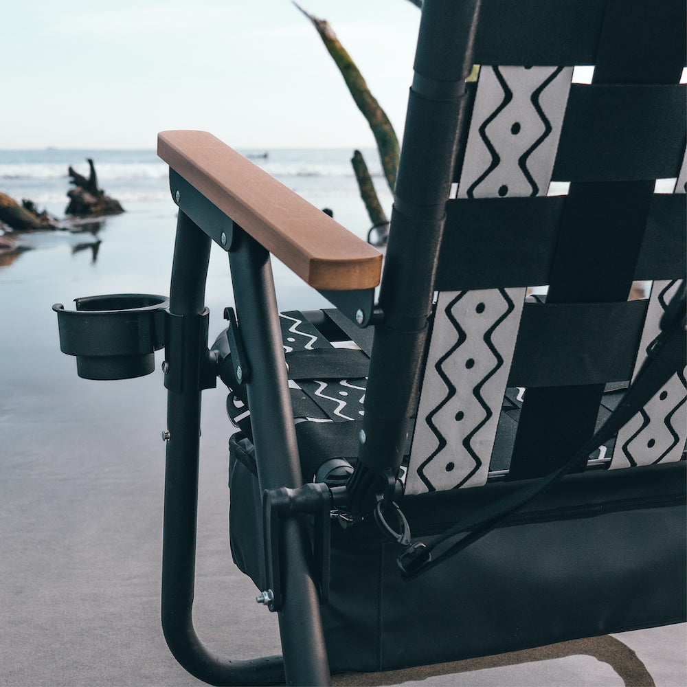 a close up shot of the voyager beach chair showing the quality build materials and detail in quality craftsmanship with surfers padling up a point break wave in the background.
