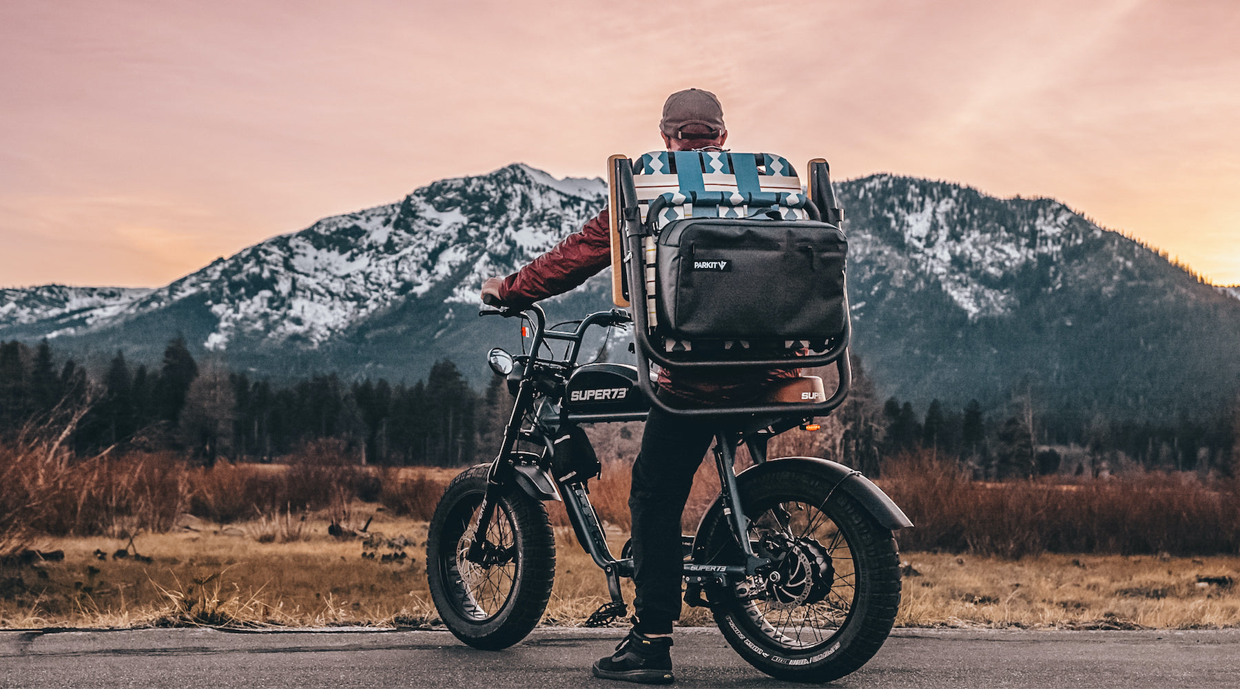 Man with super73 electric bike carrying his Voyager outdoor chair in classic blue like a backpack.