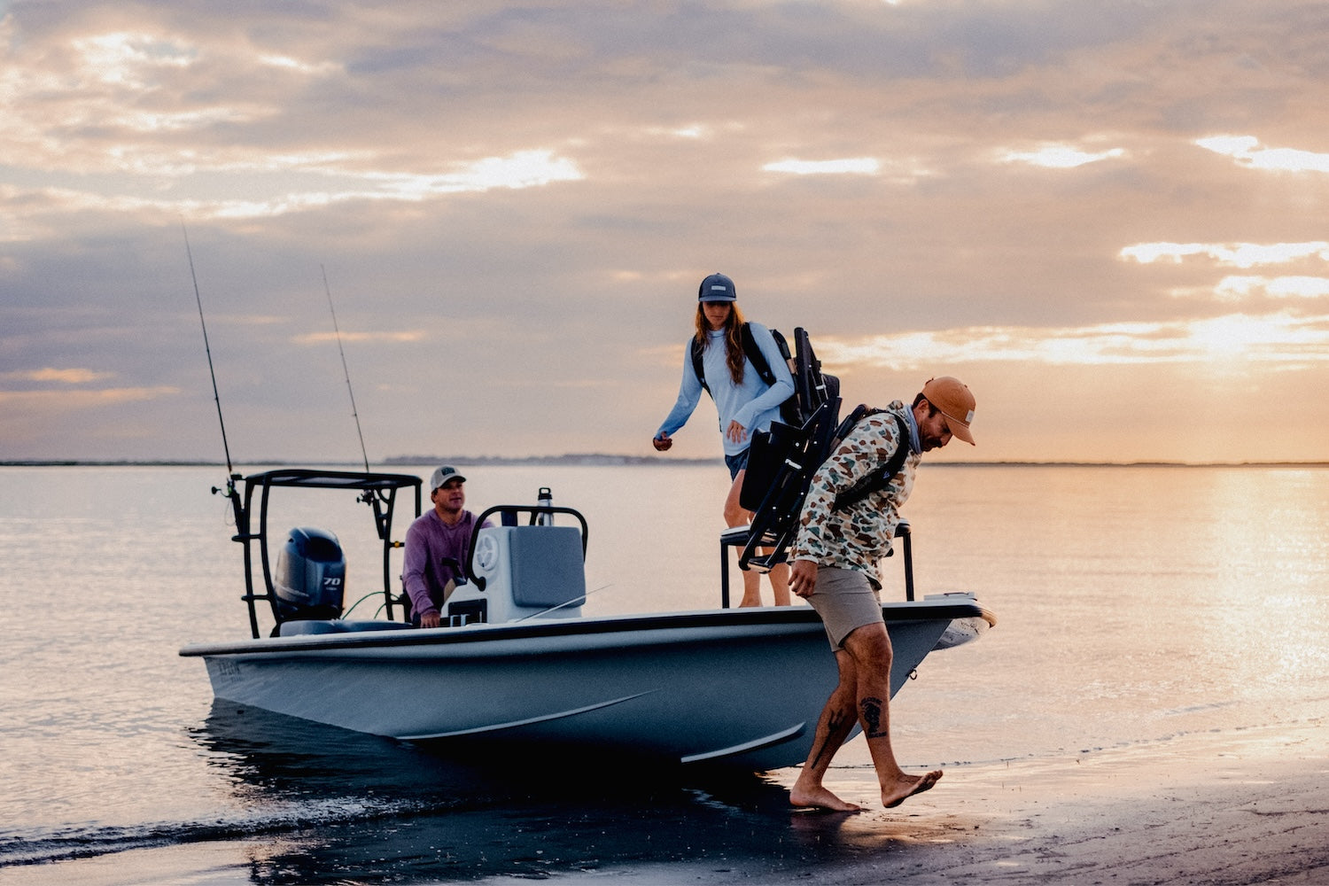 3 friends puling up on the short in the boat and getting out of the board with voyager beach chairs to watch the upcoming sunset.
