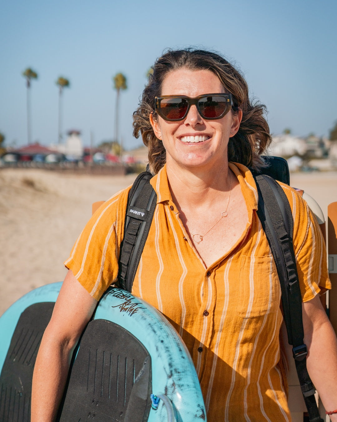 Jodie Nelson surfer and breast cancer advocate with PARKIT outdoor chair and surfboard on California beach