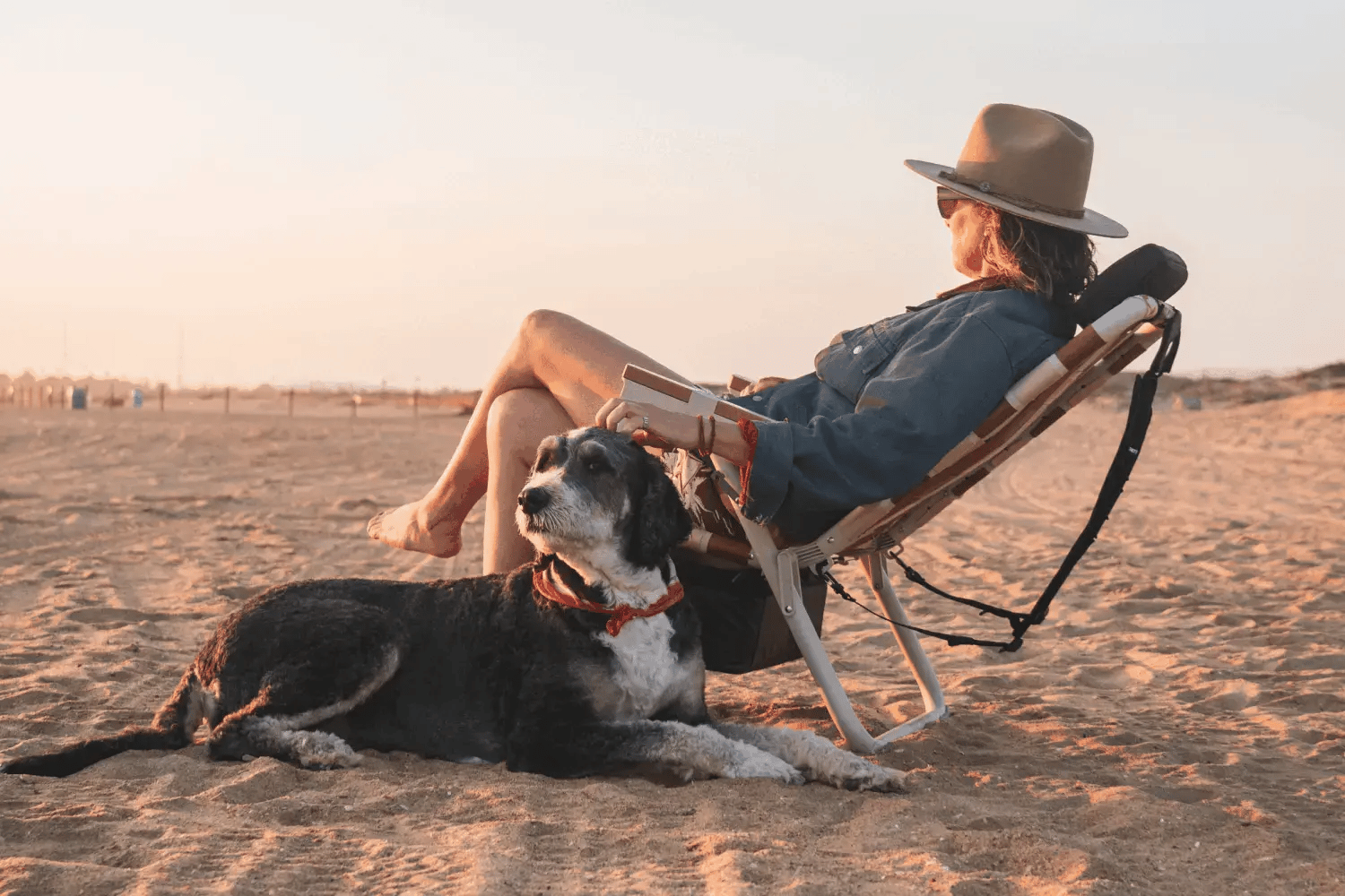 Jodie Nelson relaxing in the PARKIT Eclipse Recliner Wild 4 Boobies beach chair at sunset with her dog on the sand, part of the Keep A Breast collaboration.