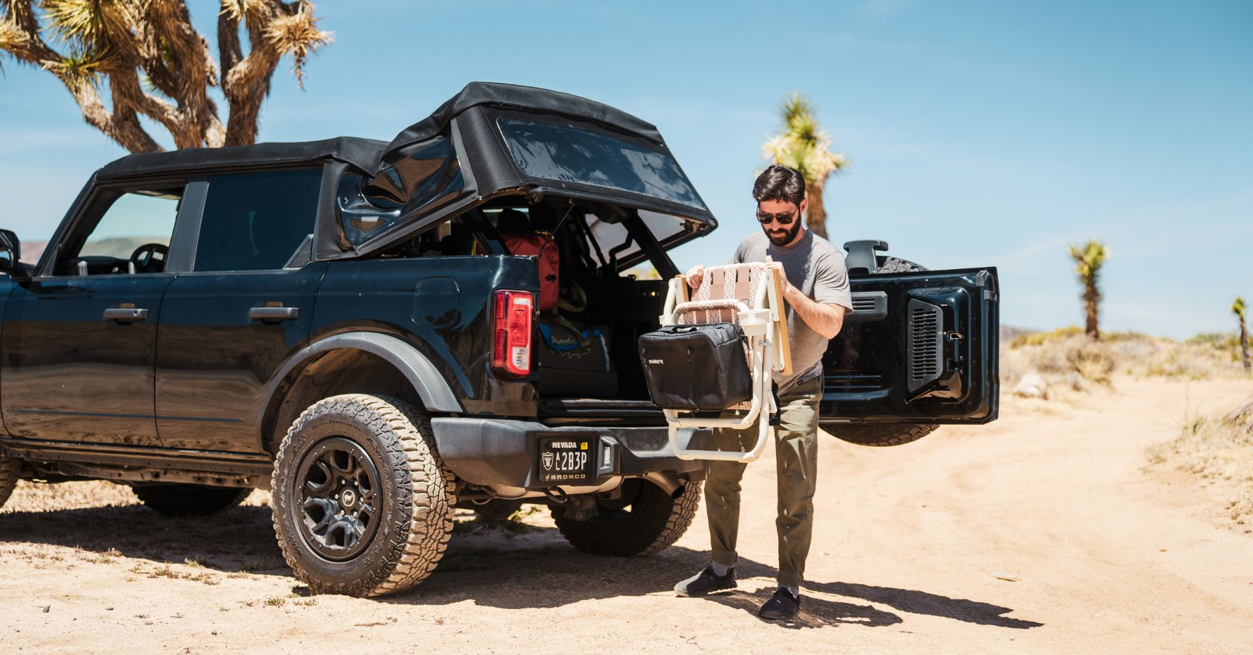 a man unloading his camping chair from PARKIT in joshua tree with a black ford bronco 
