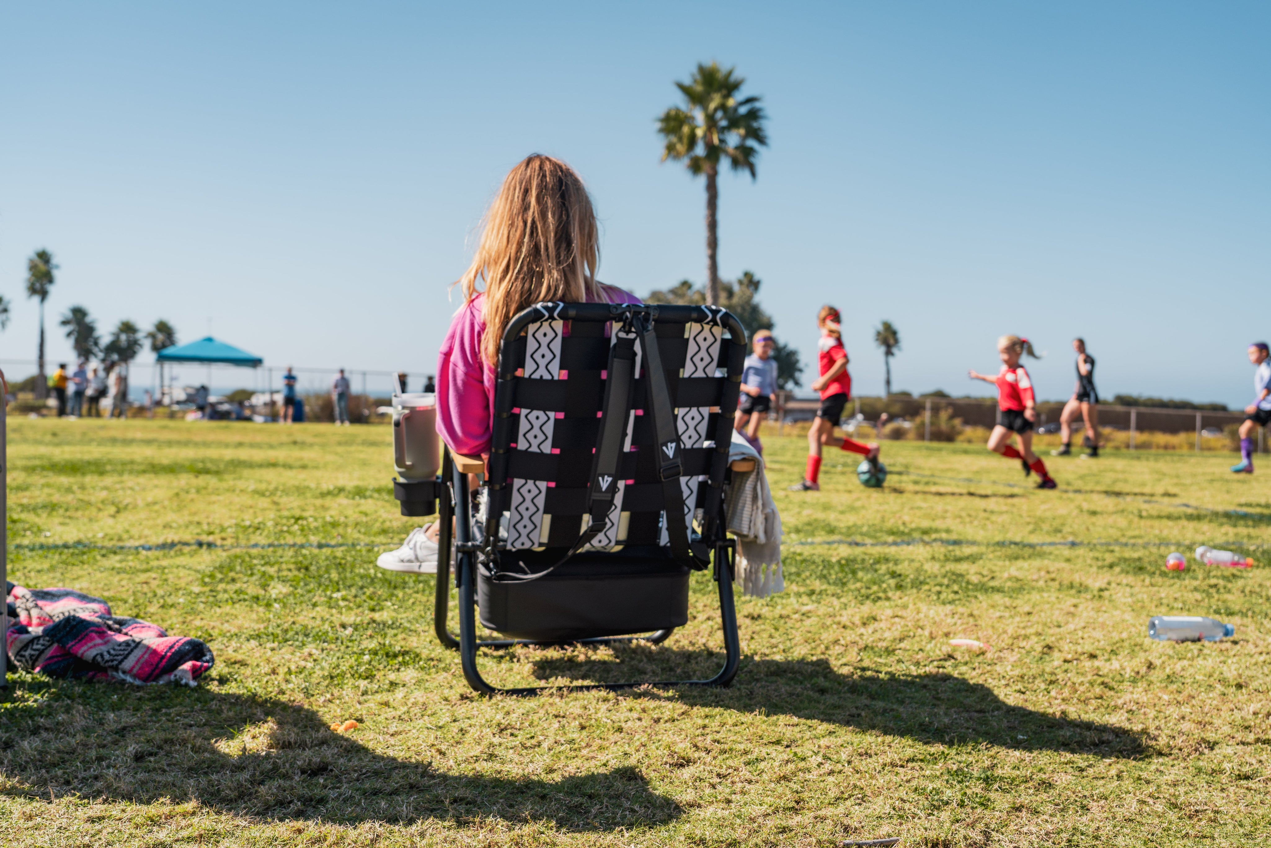 Mom sitting in Parkit Chair watching kids play soccer