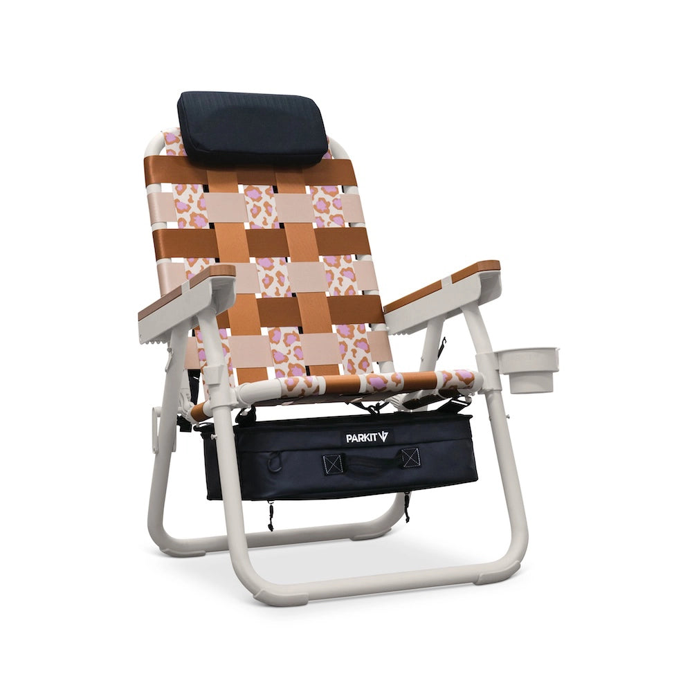 PARKIT Voyager Chair in Keep A Breast “Wild for Boobies” pattern featuring tan, cream, and pink leopard-inspired woven webbing, white powder-coated steel frame, wooden armrests, padded headrest, built-in cooler, cup holder, and backpack straps—limited-edition 3-in-1 outdoor chair supporting breast cancer awareness and outdoor adventure.