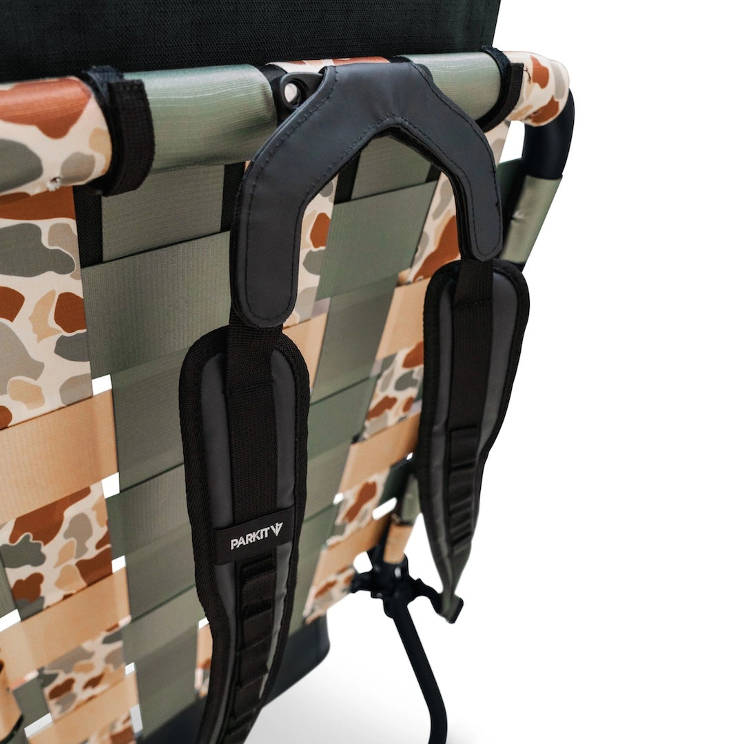Camouflage-patterned chair with black armrests and 'PARKIT' branding on a white background, coupled with PARKIT's overlander carrying straps, which make Eclipse and Voyager easy to carry. 