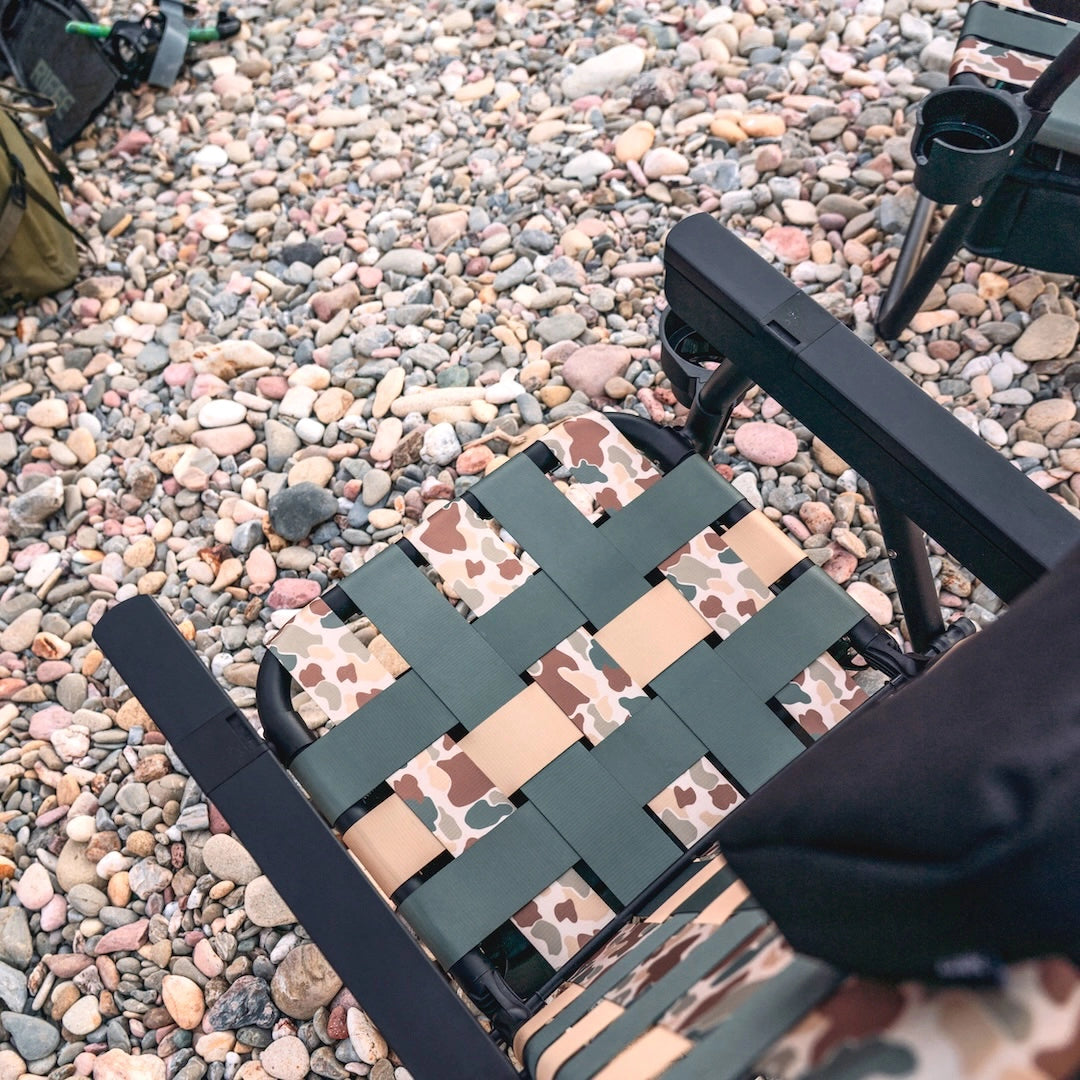 Camouflage-patterned folding chair on a pebbled surface