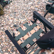 Camouflage-patterned folding chair on a pebbled surface