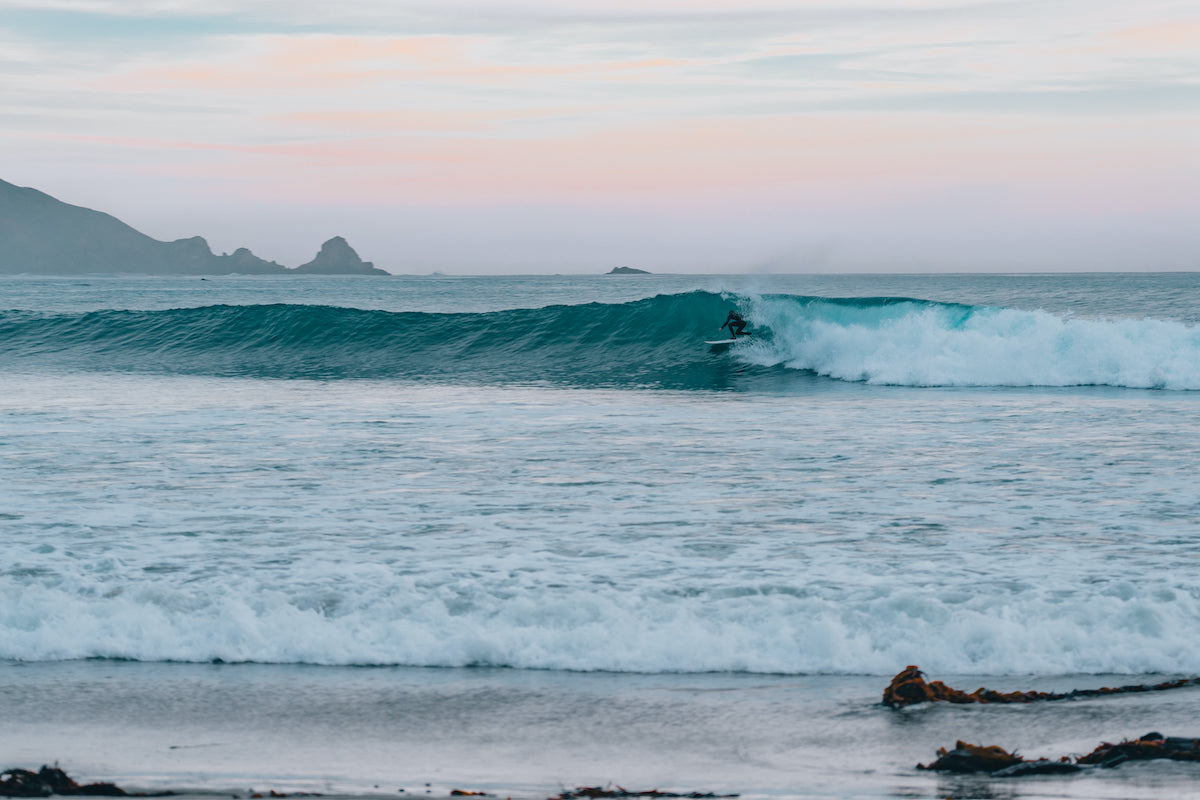 A surfer pulls into a tube at sunset in a beautiful remote area of california.