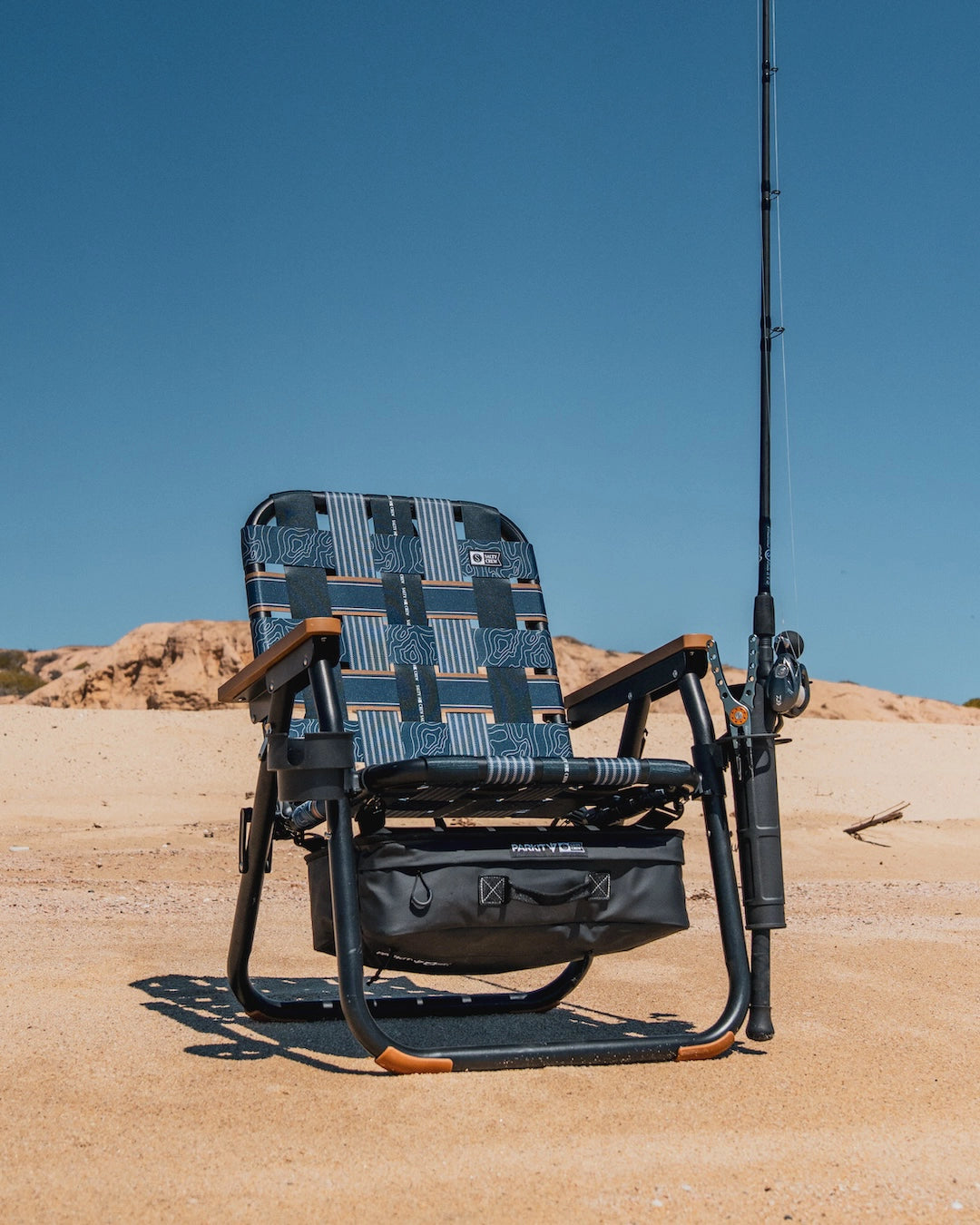 PARKIT and Salty Crew Collaboration Voyager beach boat and camping Chair with boat safe rubber feet, cooler, fishing rod accessory, cupholder, and overlander carry straps sitting on the beach on a perfect summer day sized for mobile