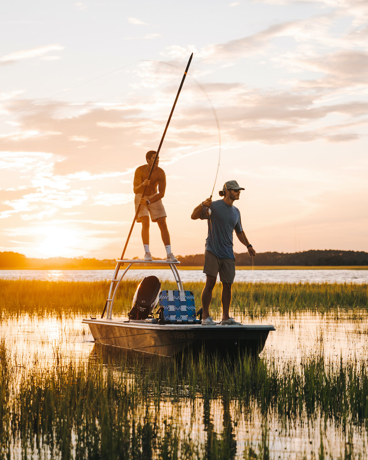 Two Men Fishing on a boat in the marshlands of the Carolinas with a Voyager outdoor chair from PARKIT serving as the main seat and center console while they fish
