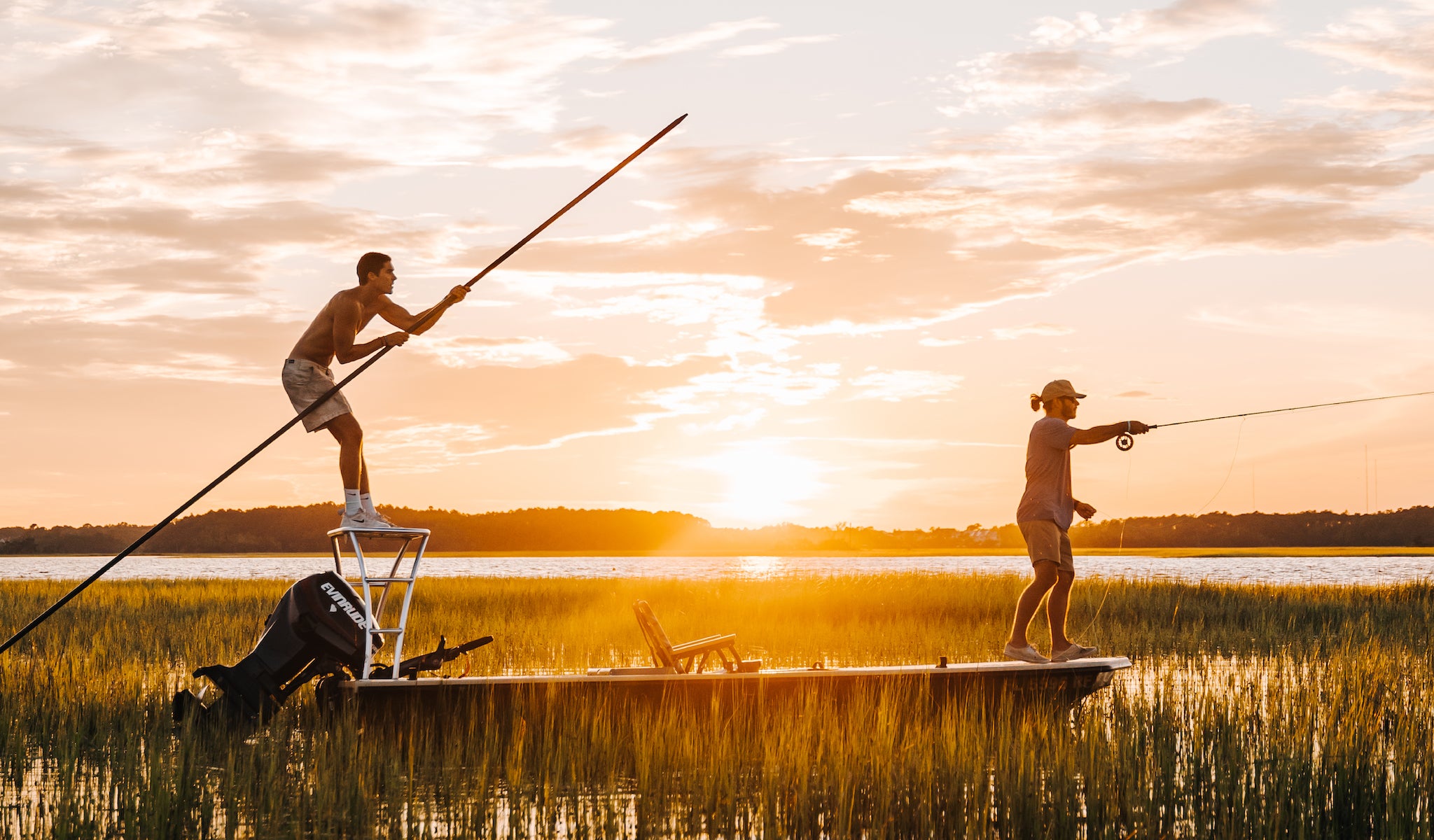Two men fishing  in the marshland off the coast of the Carolina's with a voyager outdoor chair as the center console on their boat.