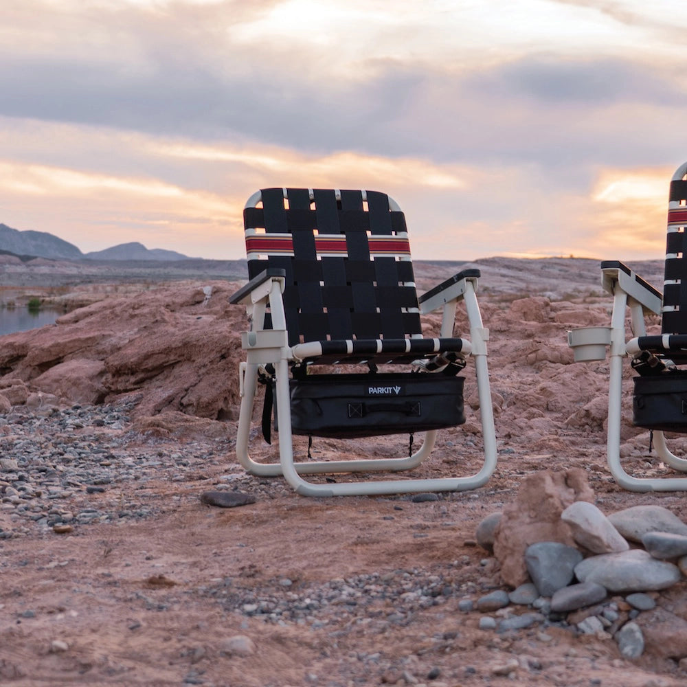 Foldable chair with a striped pattern in a desert landscape during sunset.