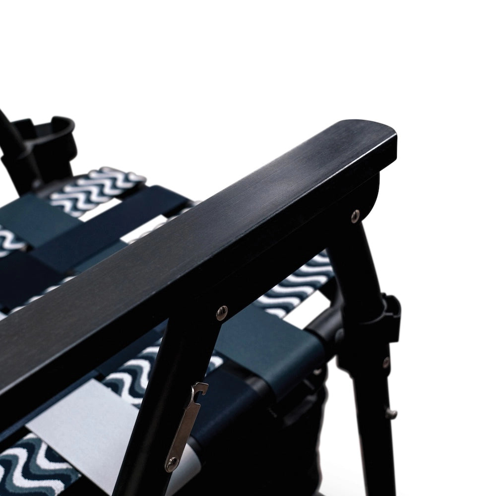 Close-up of a black wood armrest with a white background and the seat of the chair in view
