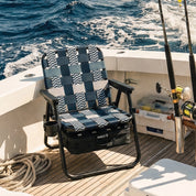Chair with a blue and white pattern on a boat deck with fishing equipment and ocean view.