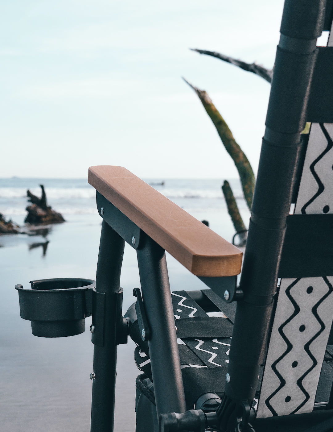 A zoomed in shot of the PARKIT Voyager Chair Arm rest with the ocean in the background. You can also see the Voyager Chair Cupholder