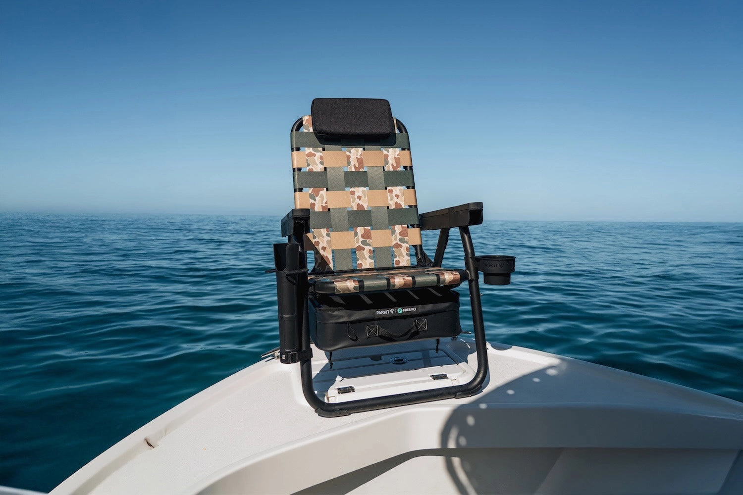 PARKIT x Free Fly Eclipse Recliner chair in Vintage Camo pattern secured on the bow of a boat, featuring the OutPost Accessory Mount and cup holder, surrounded by open blue ocean, showcasing premium 3-in-1 design, durable construction, and adventure-ready comfort built for life at sea.