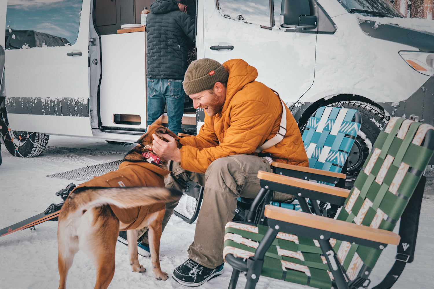 A man and his dog sitting infront of their merceded sprinter van in their PARKIT voyager outdoor chairs in the parking lot at stump ally on mammoth mountain.