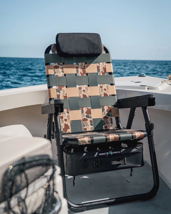 PARKIT x Free Fly Eclipse Recliner chair in Vintage Camo pattern secured on the bow of a boat, featuring the OutPost Accessory Mount and cup holder, surrounded by open blue ocean—showcasing premium 3-in-1 design, durable construction, and adventure-ready comfort built for life at sea.